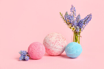 Bath bombs and vase with flowers on pink background