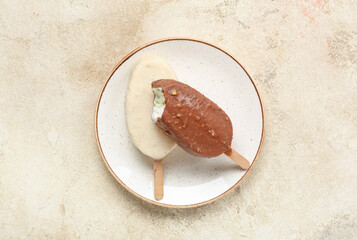 Plate with tasty chocolate covered ice cream on light background