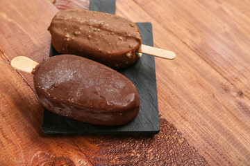 Board with tasty chocolate covered ice cream on wooden background