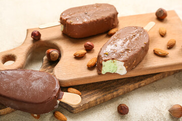 Wooden board with tasty chocolate covered ice cream on table, closeup