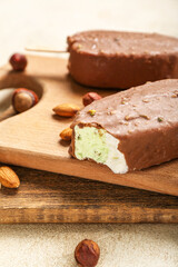 Wooden board with tasty chocolate covered ice cream on table, closeup