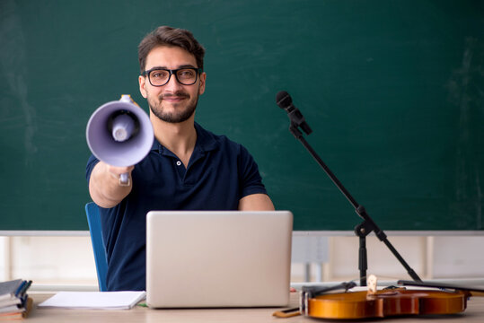 Young male music teacher holding megaphone in the classroom