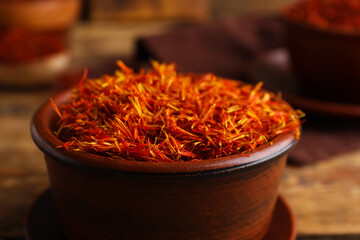Fototapeta premium Bowls with pile of saffron on wooden background