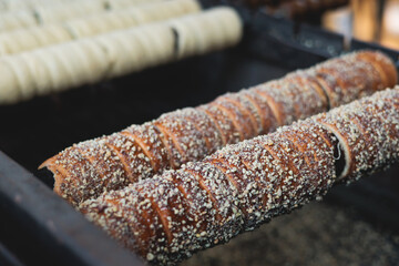 Trdelnik, traditional czech and european sweet street food, process of baking and cooking on street...