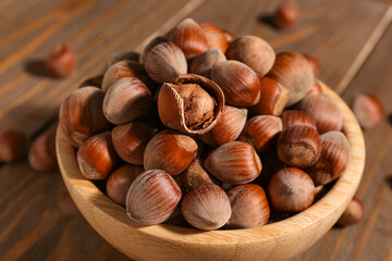Bowl with shelled hazelnuts on wooden background