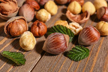 Shelled hazelnuts with leaves on wooden background