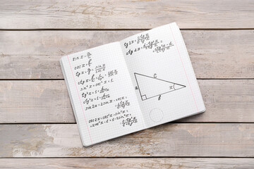 Copybook with maths formulas on grey wooden background