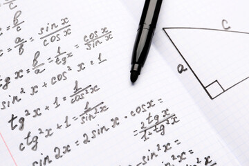 Copybook with maths formulas and pen, closeup