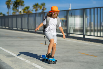 Kid on skateboard skating. Child skateboarder ride on skateboard in park. Young smiling teenager...