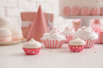 Birthday cupcakes on white table near brick wall