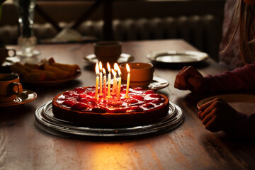 Happy child, celebrating eight years birhtday with homemade birthday cake with strawberries and burning candles, at home