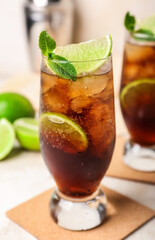 Glass of cold Cuba Libre cocktail on light background
