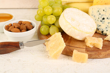Wooden board with different types of cheese on table, closeup