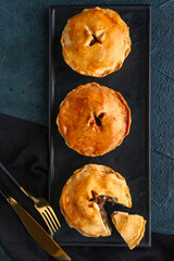 Board with tasty meat pot pies on dark background © Pixel-Shot