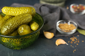 Bowl of tasty canned cucumbers with spices on black table