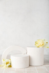 Decorative plaster podiums with daffodils on grey tile against white wall