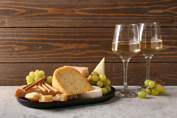 Different types of cheese, grapes and glasses with wine on table