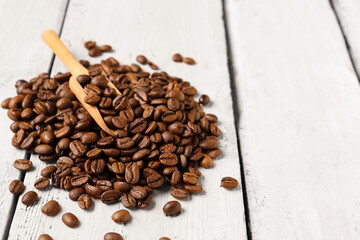 Scoop and coffee beans on light wooden background
