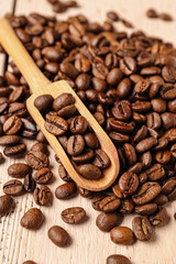 Scoop and coffee beans on light wooden background