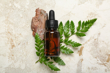 Bottle of cosmetic oil with plant twig and tree bark on grunge background