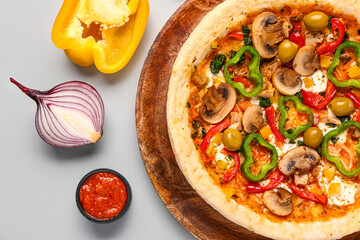 Board with vegetable pizza and ingredients on grey background