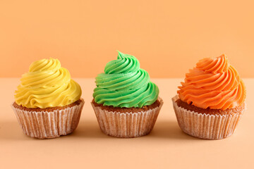 Tasty colorful cupcakes on orange background