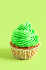 Tasty cupcake on green background