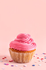 Tasty cupcake and confetti on pink background