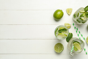Mason jars and glass of tasty mojito with fresh fruits on light wooden background