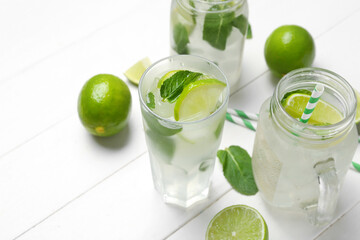 Mason jar and glass of tasty mojito on light wooden background