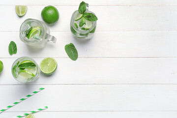 Mason jars and glass of tasty mojito on light wooden background