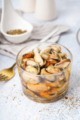 Glass bowl with pickled mussels on grey background