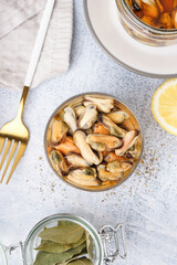 Glass bowl with pickled mussels on grey background