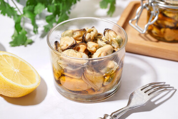 Glass bowl of pickled mussels on white background