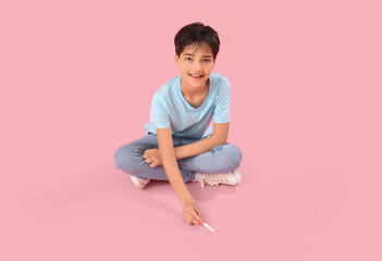 Little boy drawing with chalk piece on pink background. Children's Day celebration