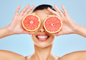 Use citrus for a brighter complexion. Studio shot of an attractive young woman posing with grapefruit against a blue background.