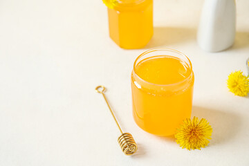 Jars with dandelion honey on white table