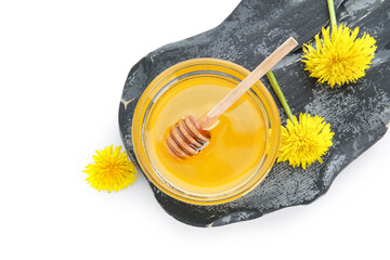 Board with bowl of dandelion honey on white background
