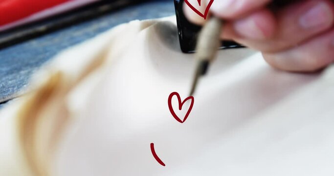 Animation of hearts over hand writing in notebook