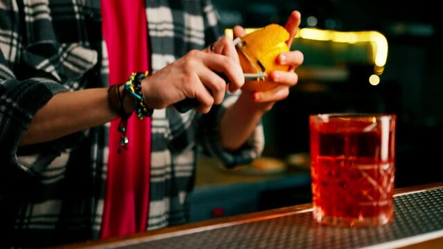 Male hands of a bartender peel an orange fruit for a cocktail with a special tool close-up
