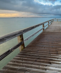 Obraz premium Empty wooden pier with dramatic sky and calm water