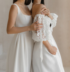 Two models or brides dressed in the classic white wedding dress with cleavage and long fancy...