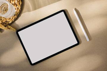 Tablet with white screen on beige background in natural light
