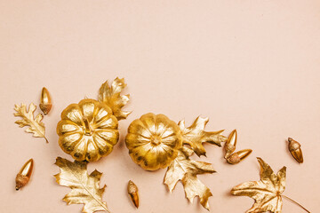 Gold painted leaves, pumpkins and acorns, autumn flat lay