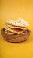Tempe chips served on a wooden plate with a yellow background