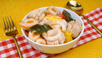Seblak jeletot indonesia traditional food with any variant toping, over yellow background.
