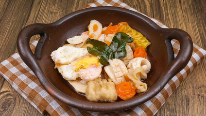 Indonesian street food cuisine, seblak in traditional wok pan, over wooden table