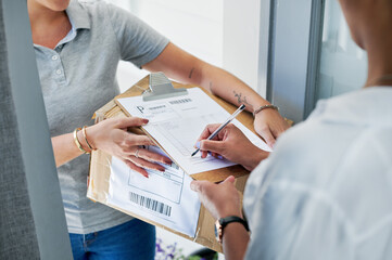 Sign here, please. an unrecognizable woman standing and signing for her package from the courier.