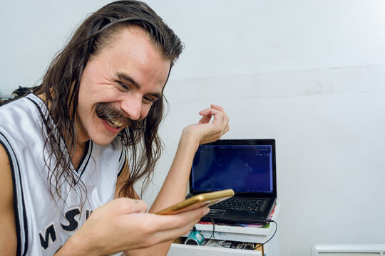 very happy young gender non-binary person laughing out loud using the phone