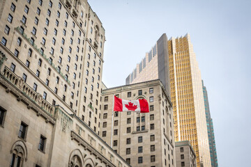 Canadian flag in front of a business building and an older skyscraper in Toronto, Ontario, Canada